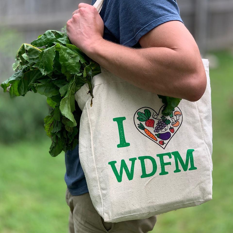 A customer shows off their love for their local farmers market on a tote bag